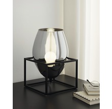 Bordslampa med glaskropp och metallram på ett bord