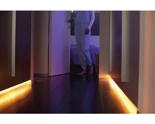 Hall med LED-belysning under skåpen och en person i bakgrunden