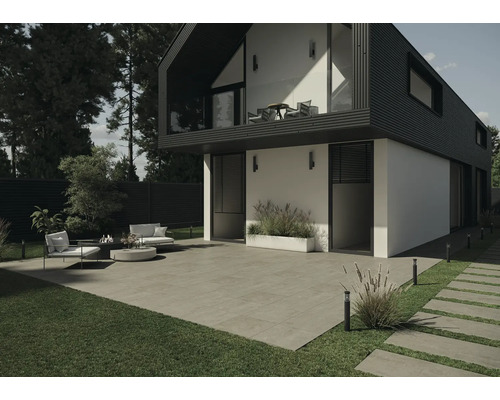 Uteplats med moderna hus med terrassplattor, gräsmatta och trädgårdsmöbler.