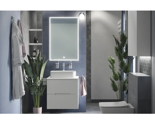 Modernt badrum med tvättställ, spegel med belysning och toalett.