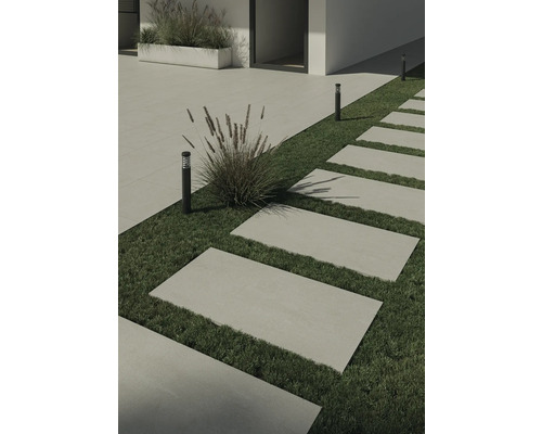 Trädgårdsgång med betongplattor på gräsmatta och utomhusbelysning