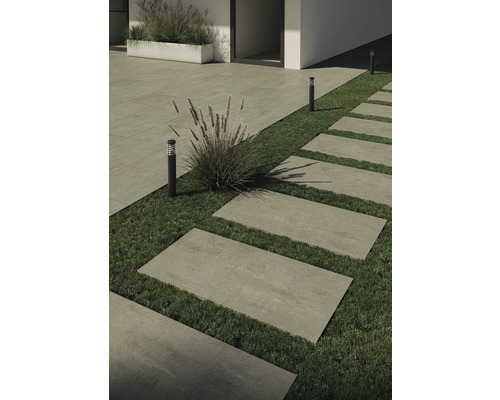 Utomhusbild med stenplattor som gångväg och gräsmattor, kombinerat med plantering och utomhusbelysning.