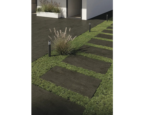 Utomhusbild med terrassplattor, gräsmatta och utomhusbelysning.