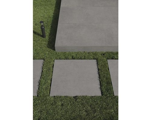 Scen med grå terrassplattor och gräsmattor, kompletterad med utomhusbelysning.