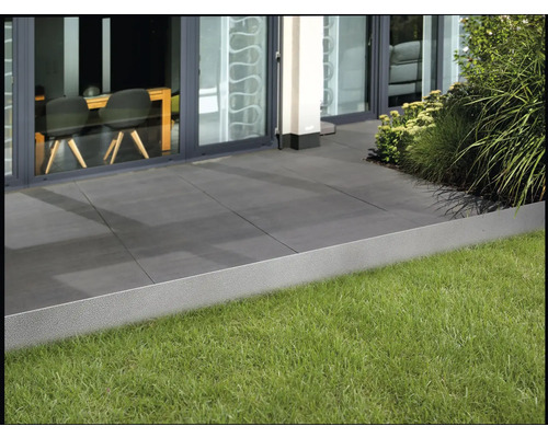 Scen med gräskant, gräsmatta och terrassplattor