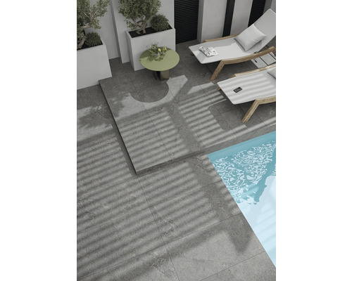 Terrass med grå stenskivor, solstolar och pool