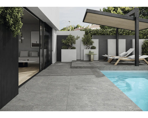 Uteplats med grå plattor, pool, solstolar och pergola