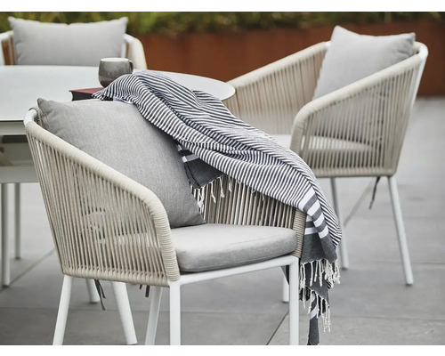 Trädgårdsscen med bord, stolar, kuddar och filt