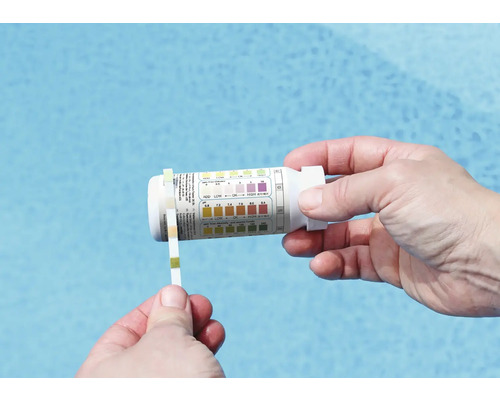 Person mäter poolens pH-värde med testremsor