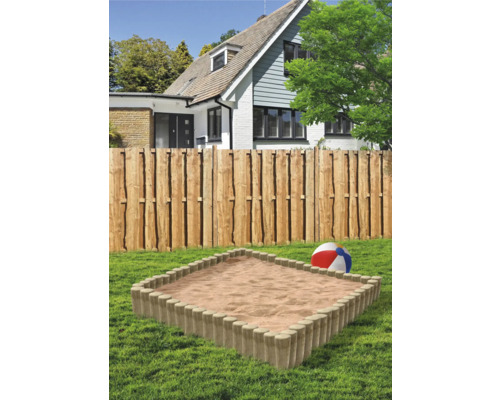 Sandlåda i trädgården med trästaket och hus i bakgrunden