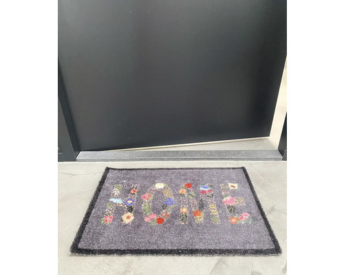 Dörrmatta med blommönster och ordet Hem framför en dörr