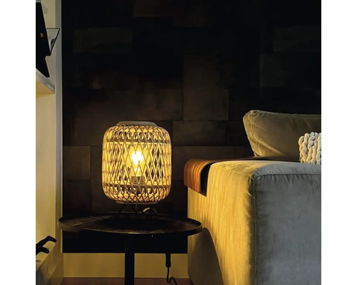 Dekorativ bordslampa i rotting bredvid en soffa på ett bord