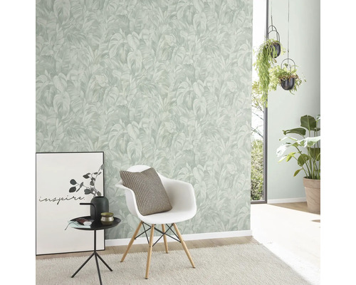 Vardagsrum med en vägg med en tapet med växtmönster, en stol och dekorativa element.
