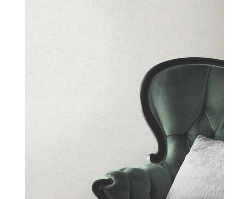 Närbild av en grön fåtölj med kudde framför en vägg