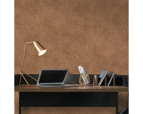 Arbetsplats med skrivbord, lampa, bärbar dator och kontorsmaterial mot en brun vägg