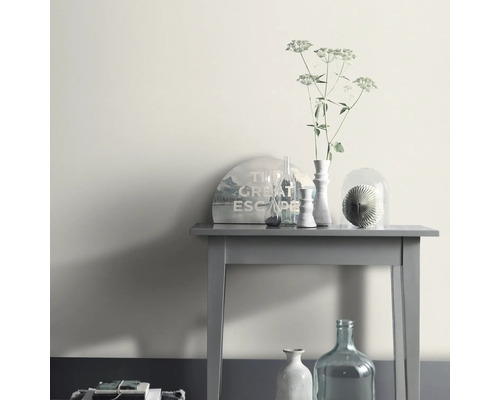 Dekorativt arrangemang på ett grått bord med vas och krukväxt.