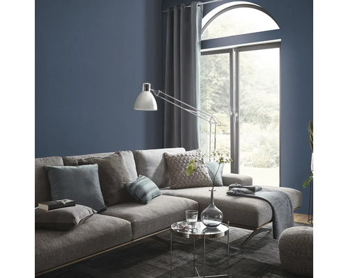 Vardagsrum med grå soffa, kuddar, lampa och fönster