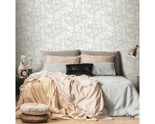 Sovrum med säng och geometrisk tapet i bakgrunden