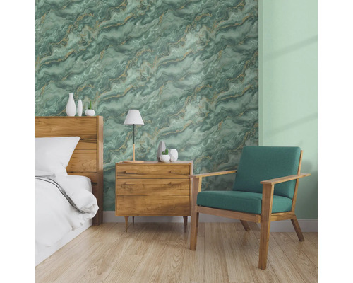 Sovrum med säng, sängbord och fåtölj framför en vägg med marmortapet.