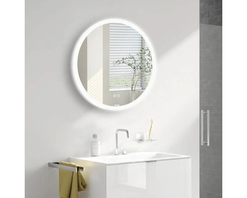 Belyst rund spegel ovanför ett handfat i ett badrum.