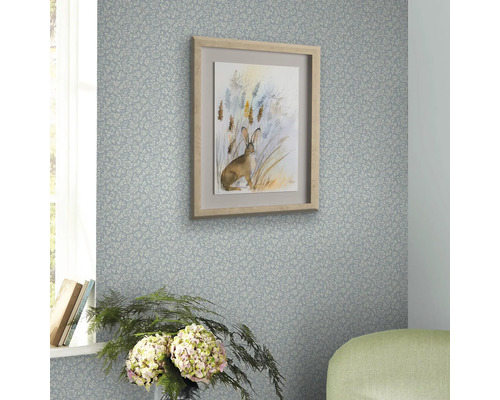 Dekorativt rum med mönstrad tapet och en inramad kaninbild på väggen