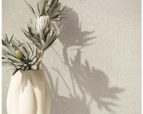 Proteablomma i vas framför tapet