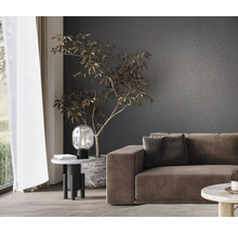 Vardagsrum med soffa, bordslampa och krukväxt framför en mönstrad vägg