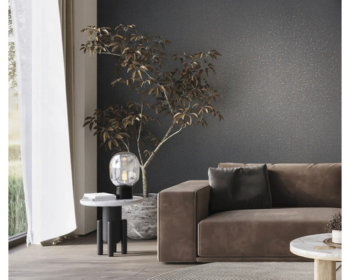 Vardagsrum med soffa, bordslampa och krukväxt framför en mönstrad vägg