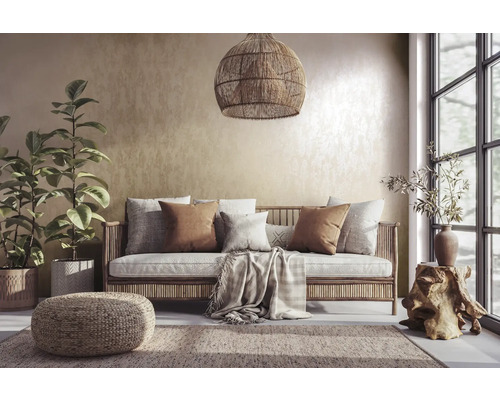 Vardagsrum med rottingsoffa, kuddar, matta och krukväxter