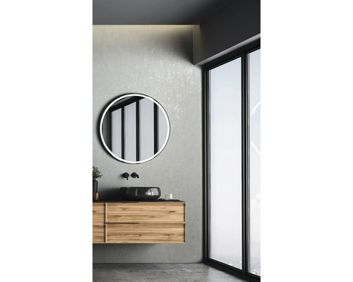 Badrum med tvättställsskåp, rund spegel och fönster