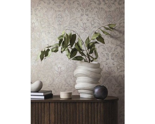 Dekorativ inredning med mönstrad tapet, byrå, böcker och vaser