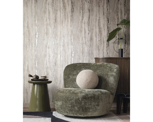 Vardagsrum med mönstrad tapet, fåtölj och sidobord.