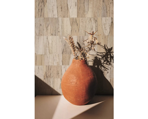 Dekorativ vas med torkade blommor på ett bord framför en strukturerad vägg