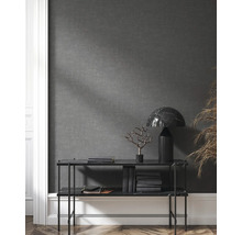 Hylla med dekorationer, böcker och lampa framför en grå vägg