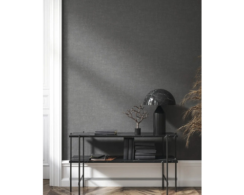 Hylla med dekorationer, böcker och lampa framför en grå vägg