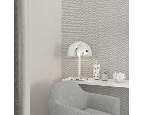 Miljöbild med fåtölj, bordslampa och mönstrad tapet