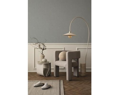 Vardagsrum med fåtölj, golvlampa, sidobord, dekoration och matta för en mysig atmosfär