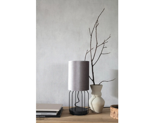 Dekorativ bordslampa med tygskärm och metallram på ett bord