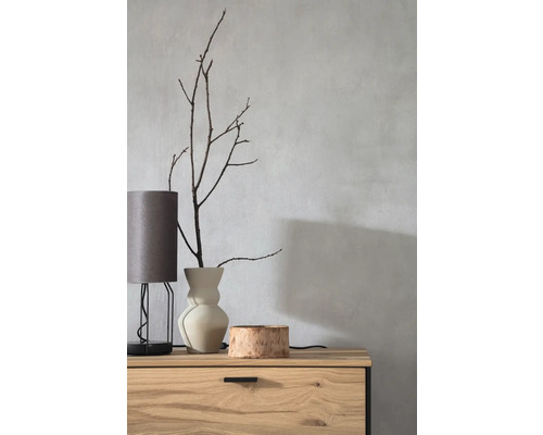 Dekorativ scen med bordslampa, vas med grenar och träskål på en byrå.