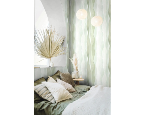 Sovrum med säng, kuddar, nattduksbord, dekoration och mönstrad tapet.