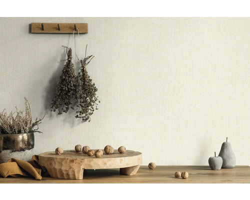 Dekorativ scen med växter, nötter och träföremål på ett bord framför en vägg