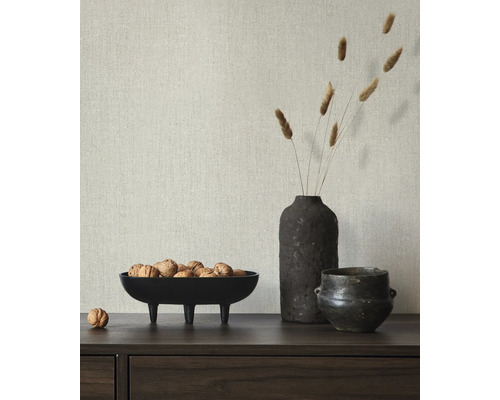 Dekorativ scen med en skål nötter, en vas med gräs och en liten kruka på en skänk