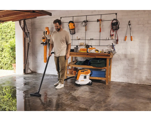 Man dammsuger golvet i ett garage med en våt- och torrdammsugare.