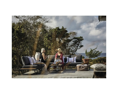 Scen med trädgårdsmöbler på en träterrass med två kvinnor, kuddar, växter, bord och väska