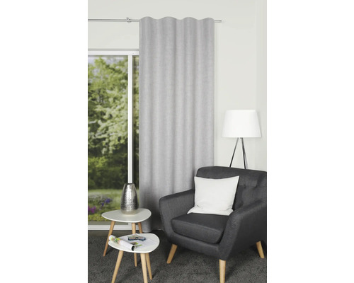 Vardagsrum med gardin, fåtölj, lampa och sidobord