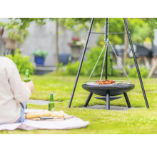 Grill med hängande galler i trädgården med en person i bakgrunden