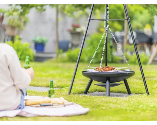 Grill med hängande galler i trädgården med en person i bakgrunden