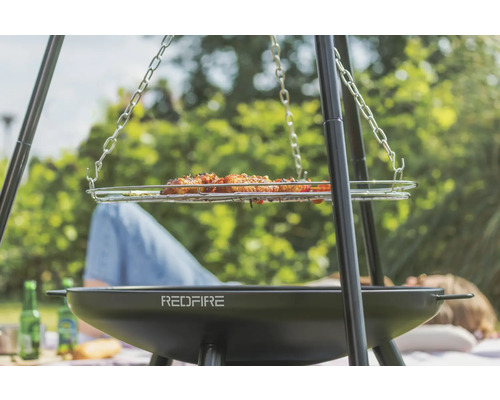 Trefotsgrill med grillad mat och RedFire-logotyp för utomhusgrillning