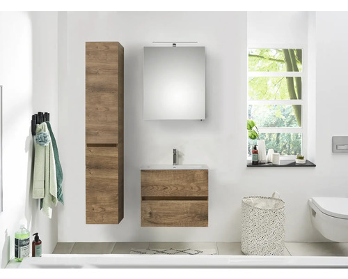 Ljust badrum med tvättställsskåp i trä, spegelskåp och högskåp.