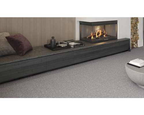 Vardagsrum med öppen spis, dekoration och grå heltäckningsmatta.